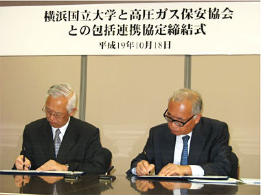 写真：協定書にサインを行うKHK作田会長（右）と横国大飯田学長