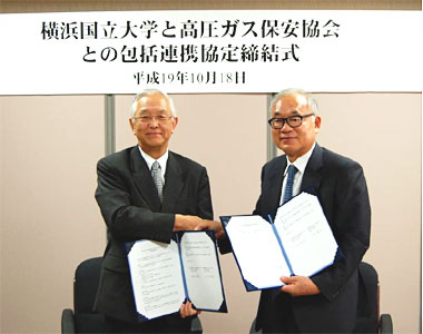 写真：協定書を取り交わした作田会長（右）と飯田学長